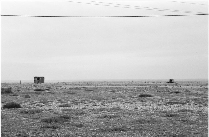 a bare monochrome terrain, two distant blockhouses